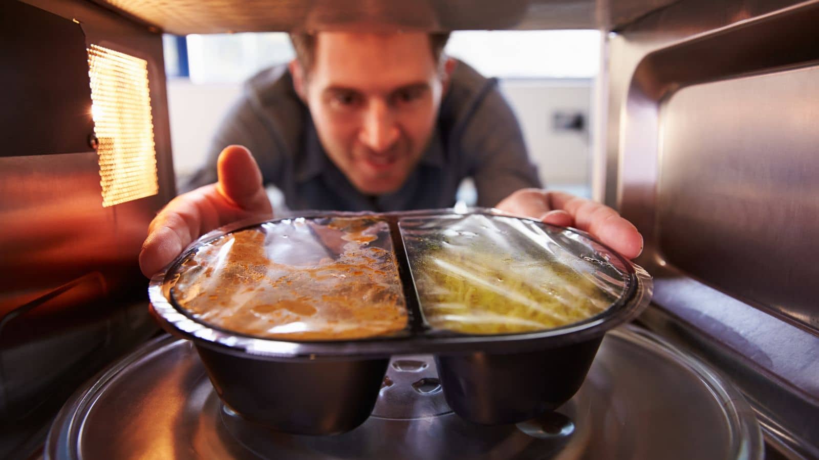 Man cooking food in the microwave.