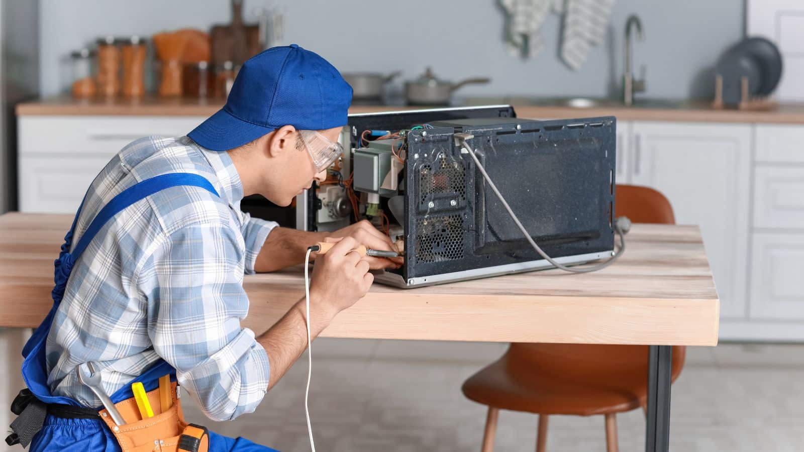 Worker Repairing Microwave oven in kitchen.